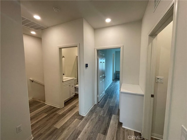 corridor featuring dark wood-style floors, visible vents, baseboards, and recessed lighting