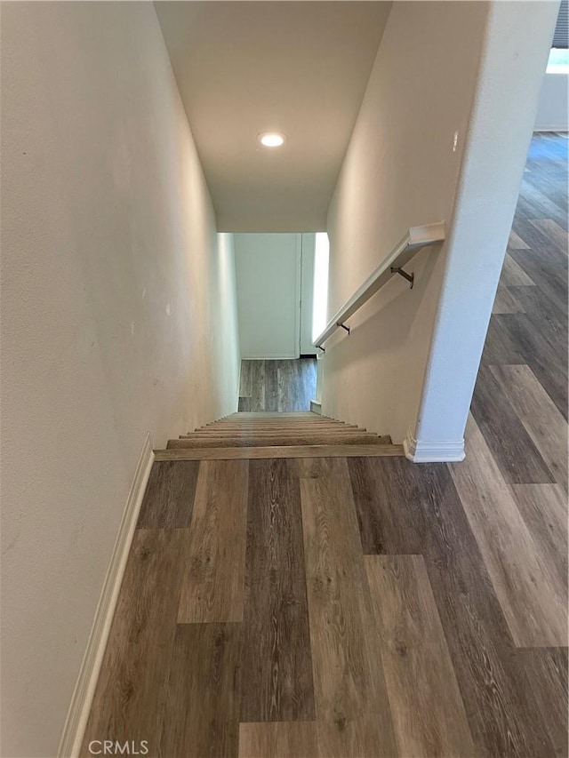 staircase featuring baseboards and wood finished floors