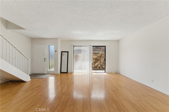 8028 Harrison St, Paramount, CA 90723 - unfurnished living room with stairway, light wood-style flooring, and a textured ceiling