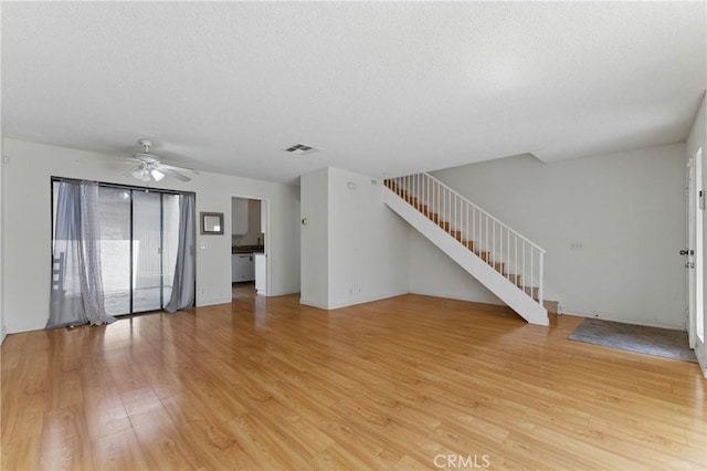 8028 Harrison St, Paramount, CA 90723 - unfurnished living room featuring stairs, a textured ceiling, and light wood-type flooring