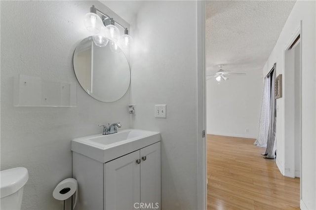 8028 Harrison St, Paramount, CA 90723 - bathroom with vanity, ceiling fan, toilet, a textured ceiling, and wood finished floors