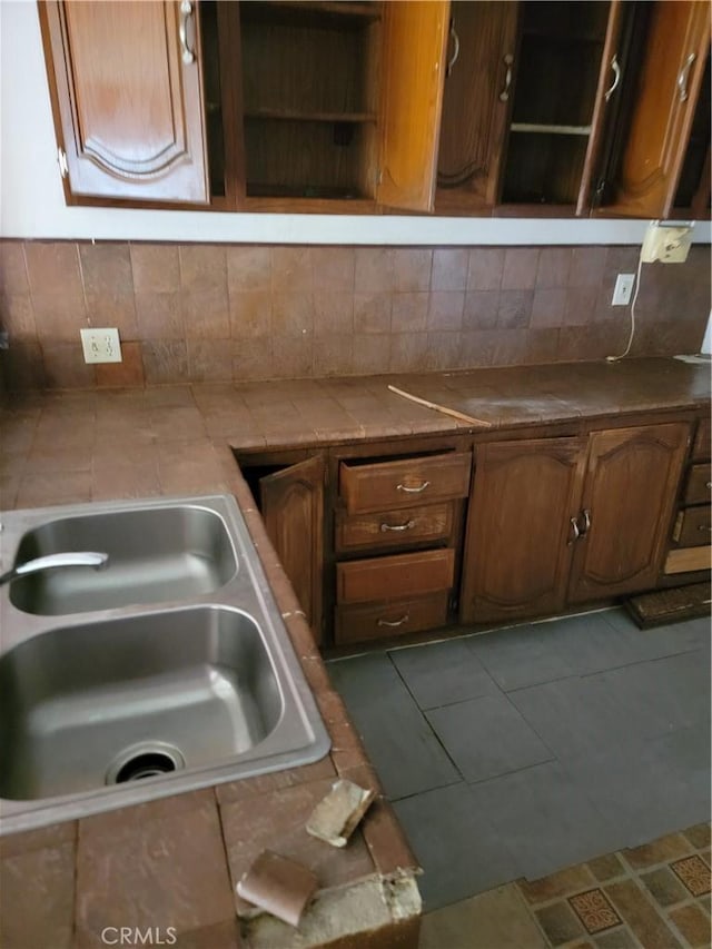 kitchen with open shelves, decorative backsplash, a sink, and tile countertops