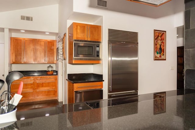 27509 Mountain Meadow Rd, Escondido, CA 92026 - kitchen featuring built in appliances, brown cabinets, dark stone counters, and a towering ceiling