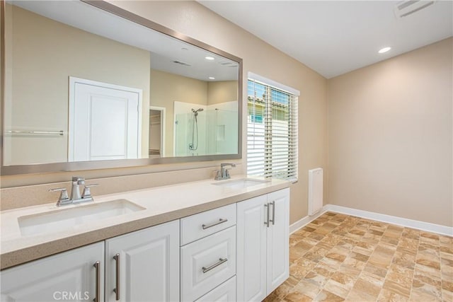 bathroom with a sink, baseboards, a shower stall, and stone finish floor