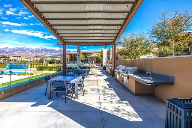 view of patio with a mountain view, grilling area, and an outdoor kitchen