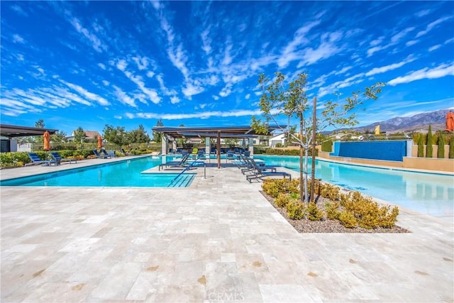 pool featuring a patio area, fence, and a mountain view