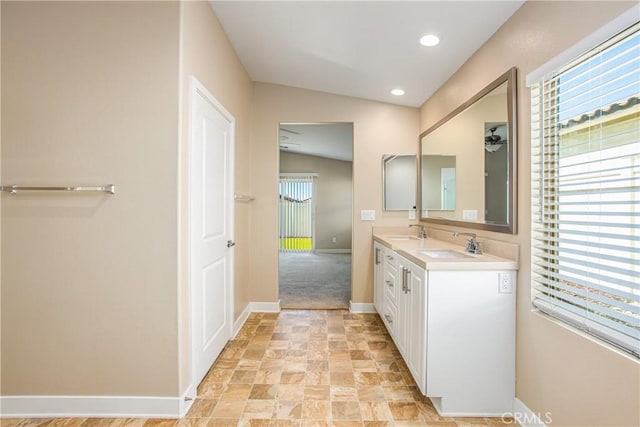 bathroom with a sink, baseboards, double vanity, and stone finish flooring