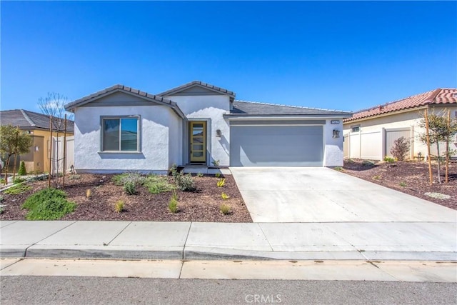 ranch-style home featuring a tiled roof, a garage, fence, concrete driveway, and stucco siding