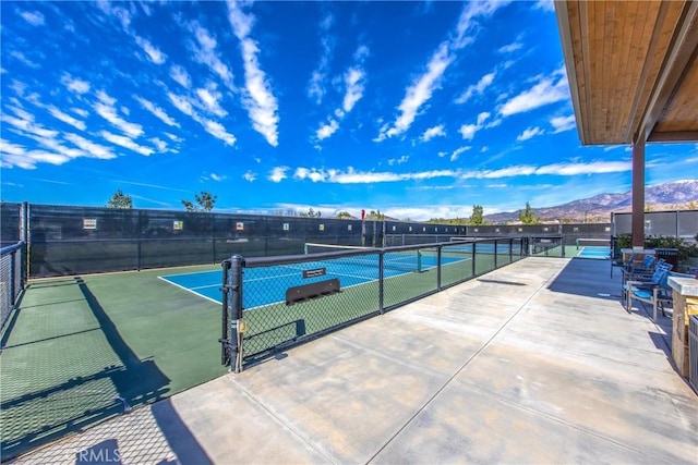 view of tennis court with fence and a mountain view