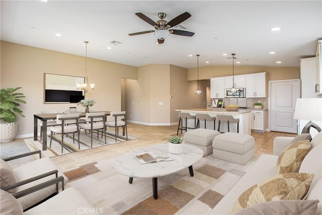living area featuring baseboards, recessed lighting, light tile patterned floors, visible vents, and ceiling fan with notable chandelier