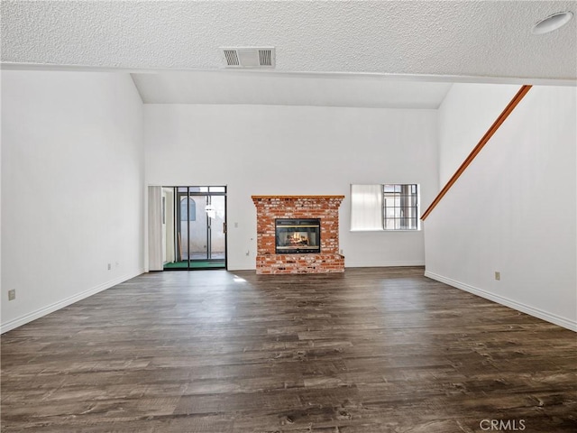 19246 Pine Way, Apple Valley, CA 92308 - unfurnished living room featuring a textured ceiling, dark wood-style floors, a brick fireplace, baseboards, and a towering ceiling