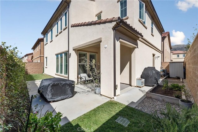 back of property with a tiled roof, a fenced backyard, a patio, and stucco siding
