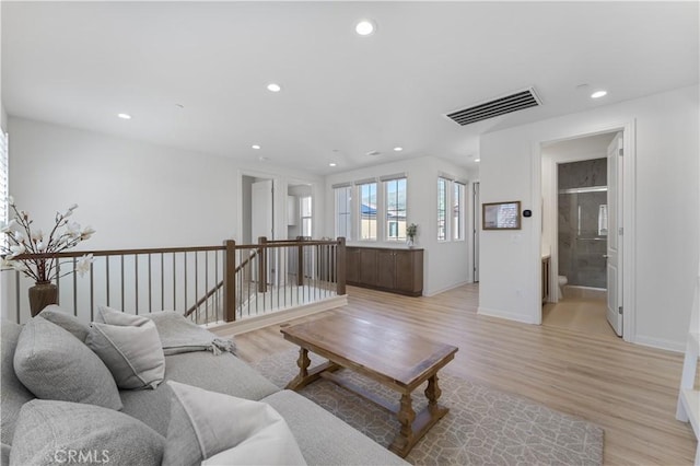 living room featuring light wood-type flooring, baseboards, visible vents, and recessed lighting