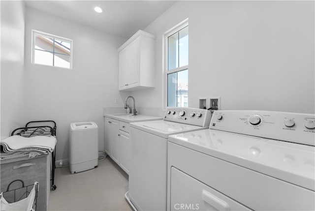 washroom featuring washing machine and clothes dryer, a sink, and cabinet space