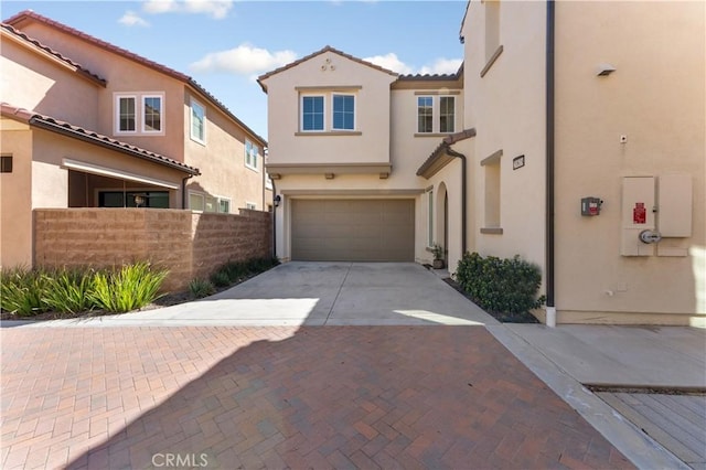 view of front of property with a tile roof, decorative driveway, an attached garage, fence, and stucco siding