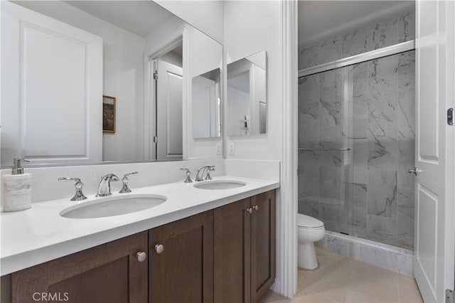 full bathroom featuring a marble finish shower, a sink, double vanity, and toilet
