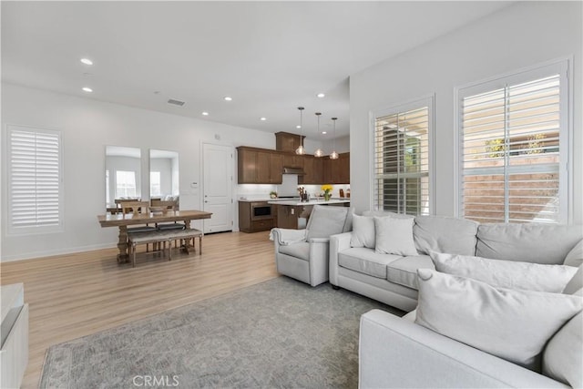 living area with recessed lighting, light wood-style flooring, visible vents, and baseboards