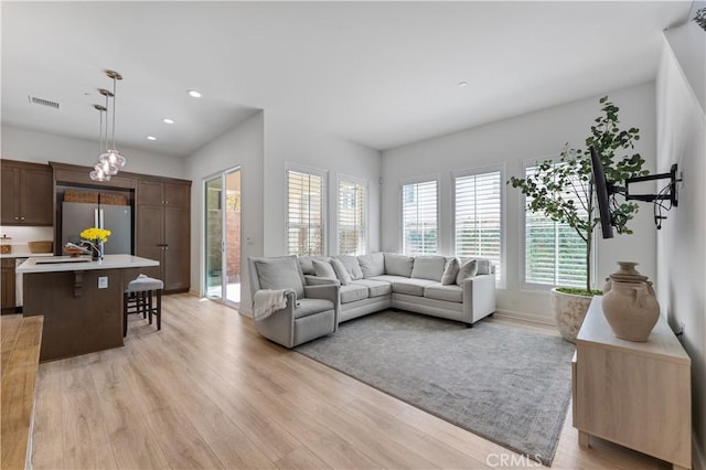 living area featuring baseboards, light wood-style floors, visible vents, and recessed lighting