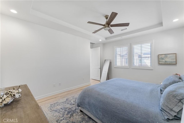 bedroom featuring light wood finished floors, visible vents, recessed lighting, and a raised ceiling