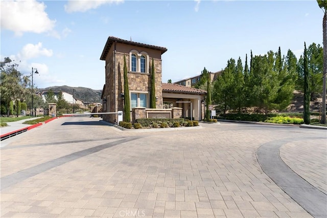 view of road with street lights, a gated entry, curbs, and a mountain view