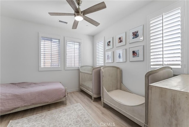 bedroom featuring light wood-type flooring, visible vents, baseboards, and ceiling fan