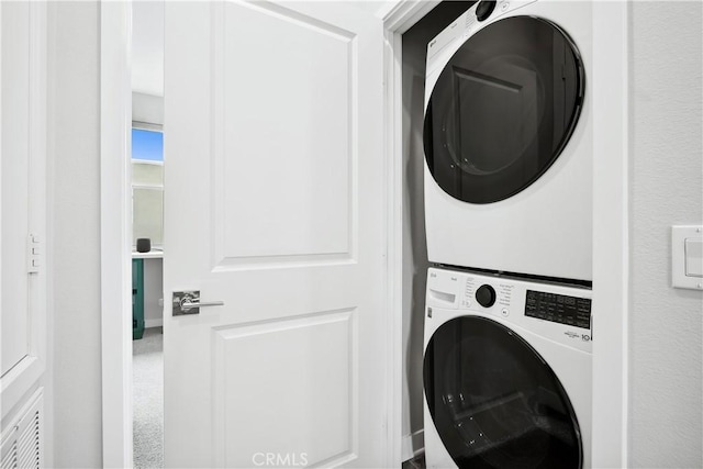 clothes washing area with stacked washer and clothes dryer and laundry area