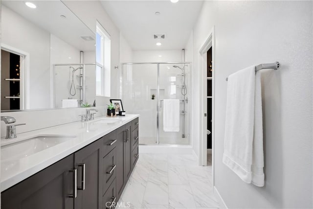 bathroom with marble finish floor, a sink, double vanity, and a shower stall