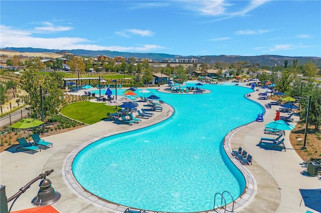 pool with a patio area, fence, and a mountain view