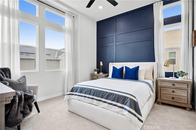 bedroom with light colored carpet, ceiling fan, baseboards, and a decorative wall
