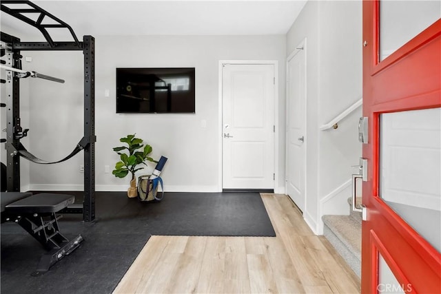 workout room with baseboards and light wood-style floors