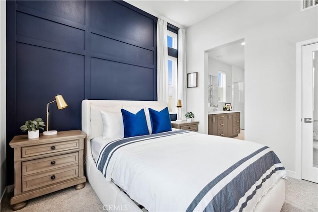 bedroom with carpet floors, baseboards, ensuite bathroom, and visible vents