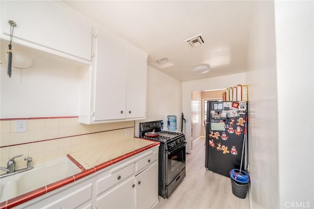 541 Elm Ave, Inglewood, CA 90301 - kitchen featuring visible vents, black appliances, a sink, white cabinetry, and tile countertops
