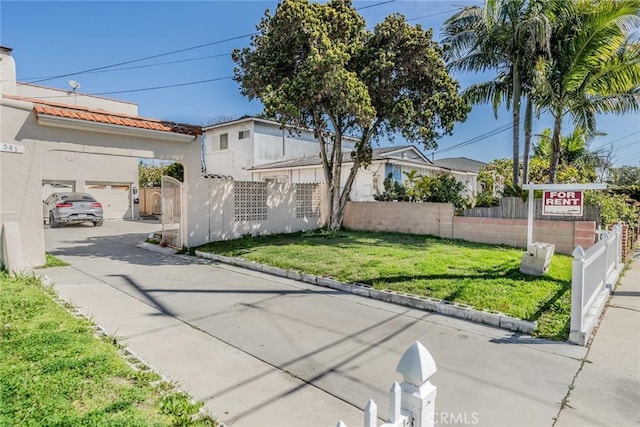 541 Elm Ave, Inglewood, CA 90301 - exterior space featuring stucco siding, driveway, a fenced front yard, a front yard, and a garage