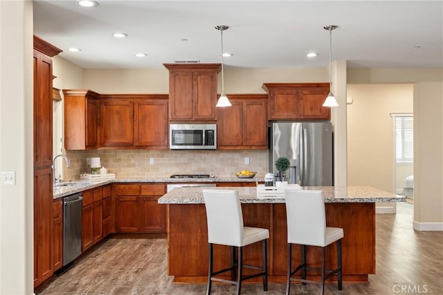 kitchen featuring tasteful backsplash, wood finished floors, stainless steel appliances, a kitchen island, and recessed lighting