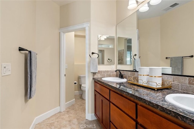full bathroom with double vanity, visible vents, toilet, a sink, and baseboards