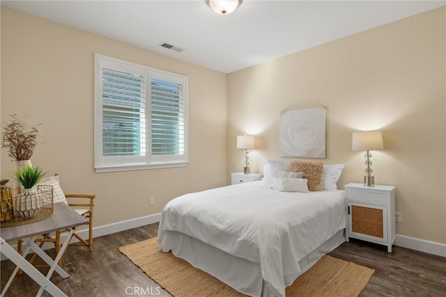 bedroom with wood finished floors, visible vents, and baseboards