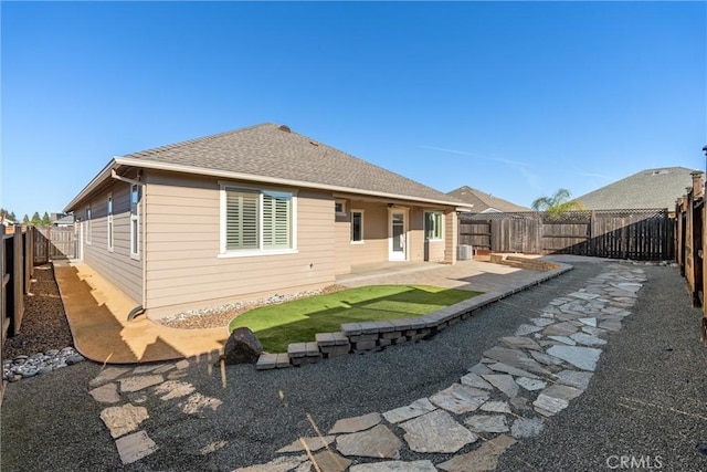 rear view of house featuring a fenced backyard, a patio, and a shingled roof
