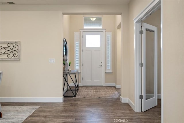 foyer featuring baseboards, wood finished floors, and visible vents