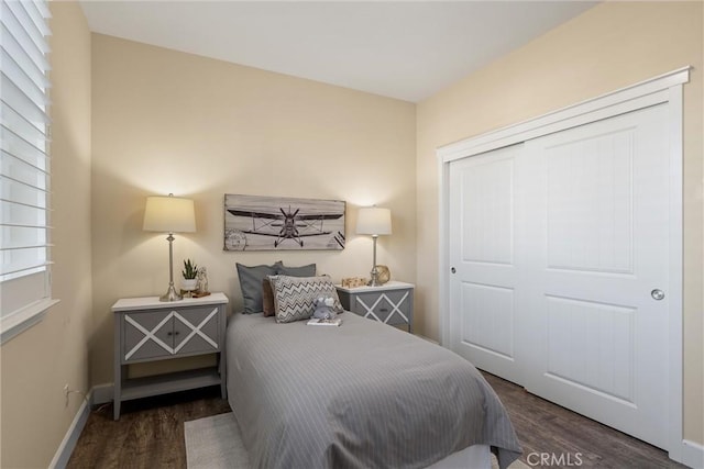 bedroom featuring baseboards, wood finished floors, and a closet