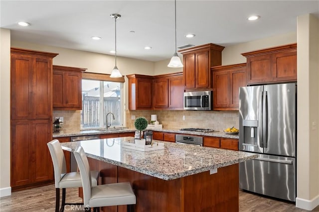 kitchen with dark wood finished floors, a kitchen island, stainless steel appliances, and a sink