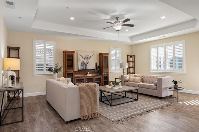 living area featuring baseboards, recessed lighting, wood finished floors, ceiling fan, and a raised ceiling