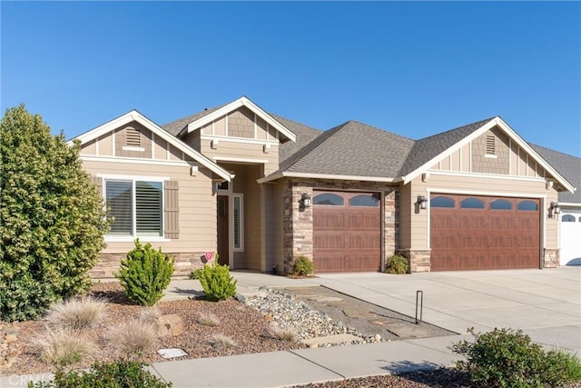 craftsman-style house featuring an attached garage, stone siding, concrete driveway, and roof with shingles