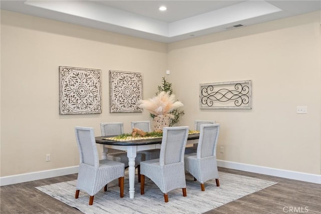 dining space featuring visible vents, baseboards, recessed lighting, wood finished floors, and a raised ceiling
