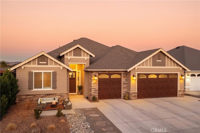craftsman-style home featuring an outdoor living space, driveway, stone siding, a shingled roof, and a garage