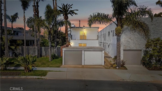 view of front of property featuring concrete driveway, fence, and a garage