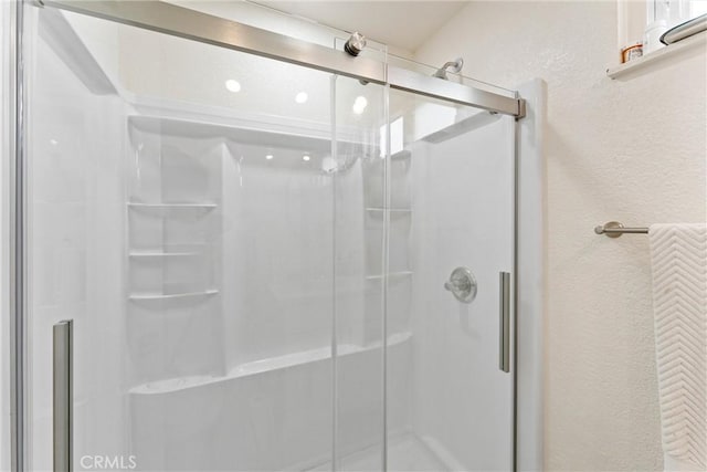 bathroom featuring a shower stall and a textured wall