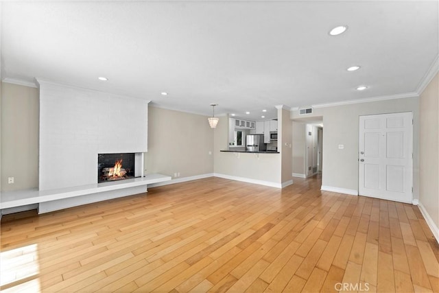 unfurnished living room with crown molding, a fireplace, visible vents, and light wood-type flooring