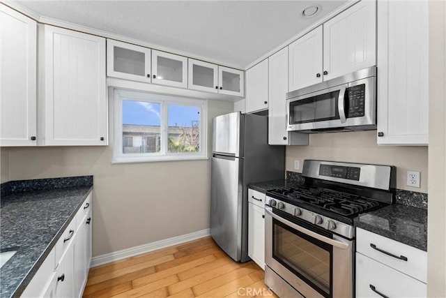 kitchen featuring white cabinets, light wood-style flooring, baseboards, and appliances with stainless steel finishes