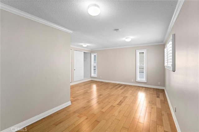 unfurnished room with light wood finished floors, a textured ceiling, crown molding, and baseboards