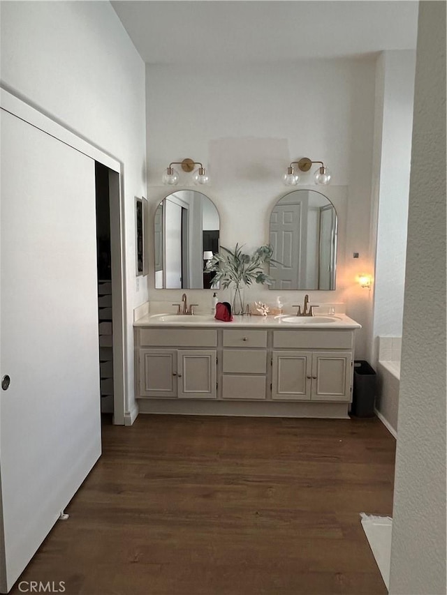 bathroom featuring double vanity, wood finished floors, and a sink